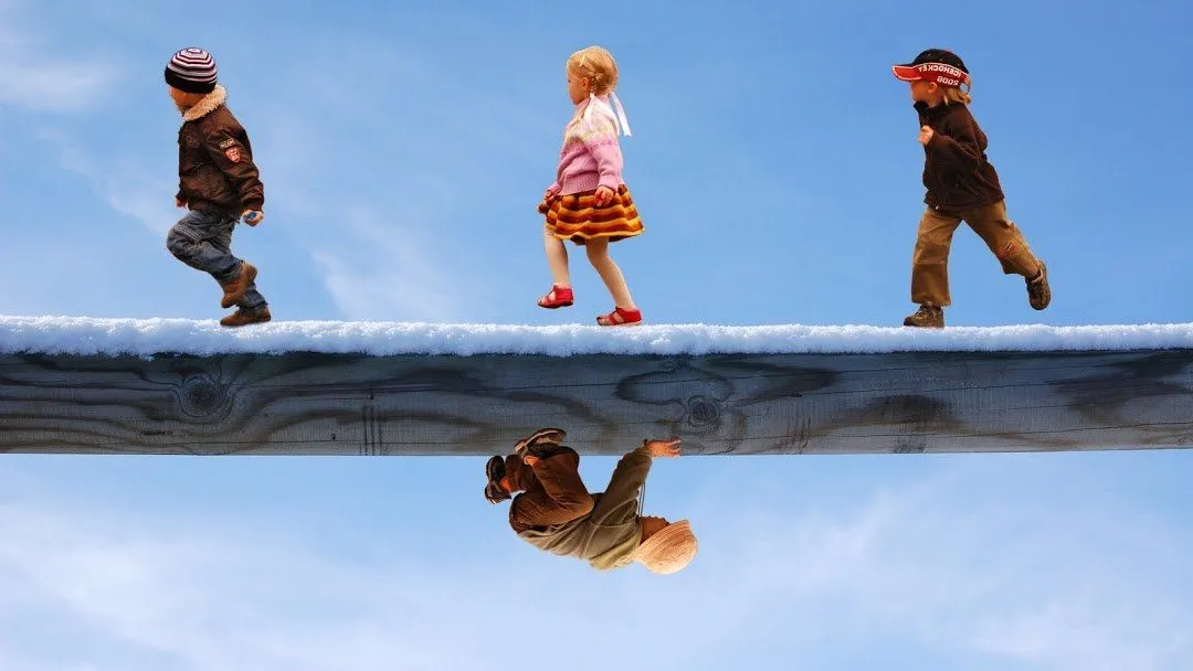 Three children balancing along a snowy log