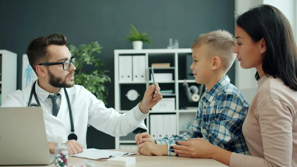 Doctor examining a young boy with his mother present during a developmental autism evaluation in Colorado