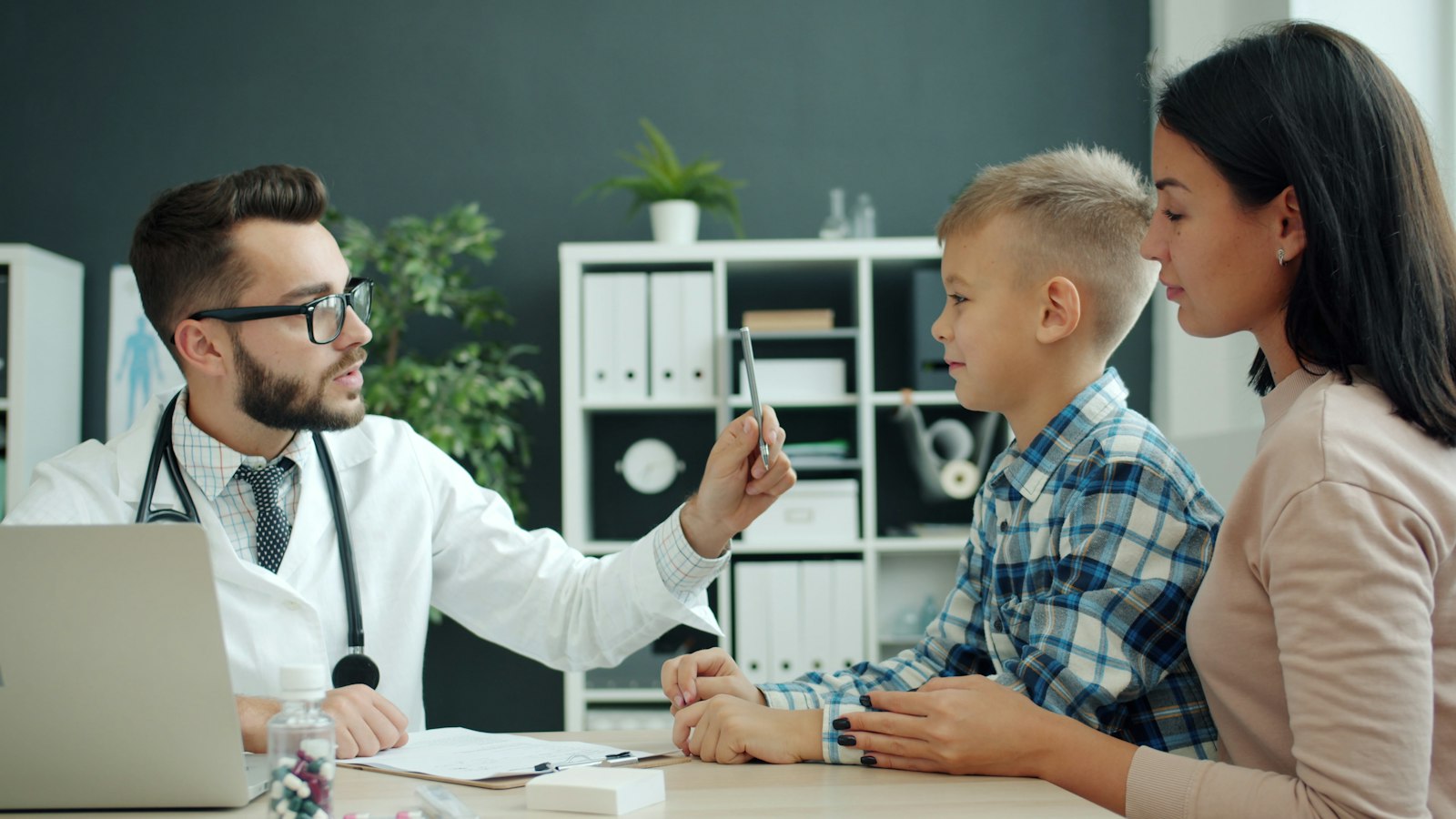Doctor examining a young boy with his mother present during a developmental autism evaluation in Colorado