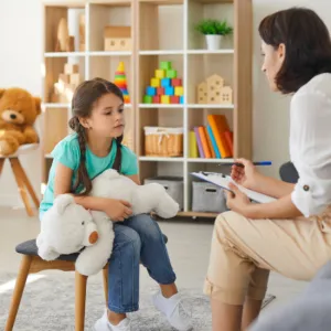 A clinician with a young girl holding a stuffed animal