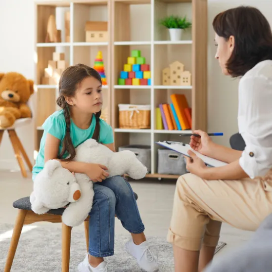A clinician with a young girl holding a stuffed animal