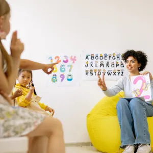 A clinician working with two children at a whiteboard