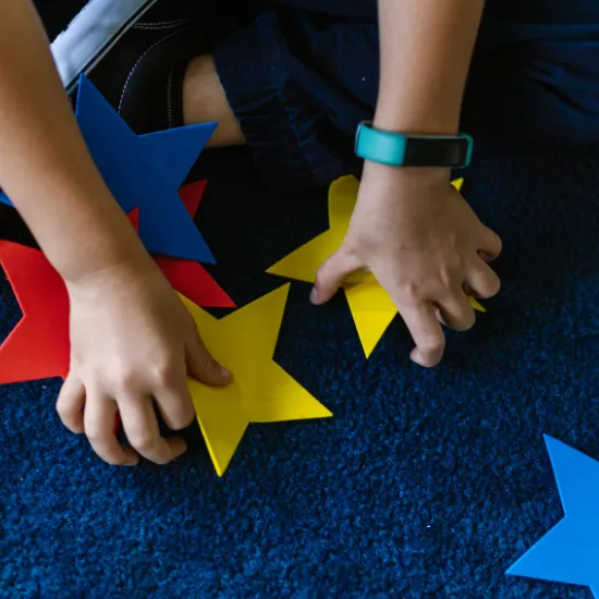 Hands arranging colorful felt stars on a mat