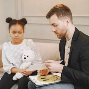 A clinician with a young girl holding a stuffed animal
